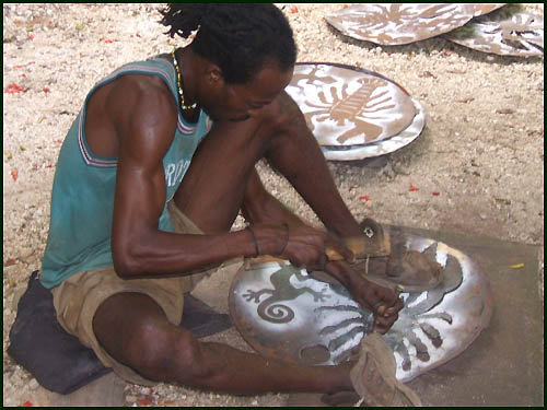 Cutting pattern into recycled steel drum in Haiti - Haitian metal tropical designs . - www.tropicdecor.com